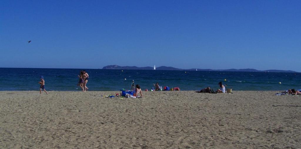 un groupe de personnes sur une plage près de l'eau dans l'établissement Plage et soleil, à Les Salins dʼHyères