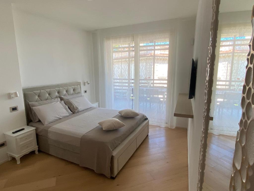 ein weißes Schlafzimmer mit einem großen Bett und Fenstern in der Unterkunft Sea View Embassy Apartment in Rimini
