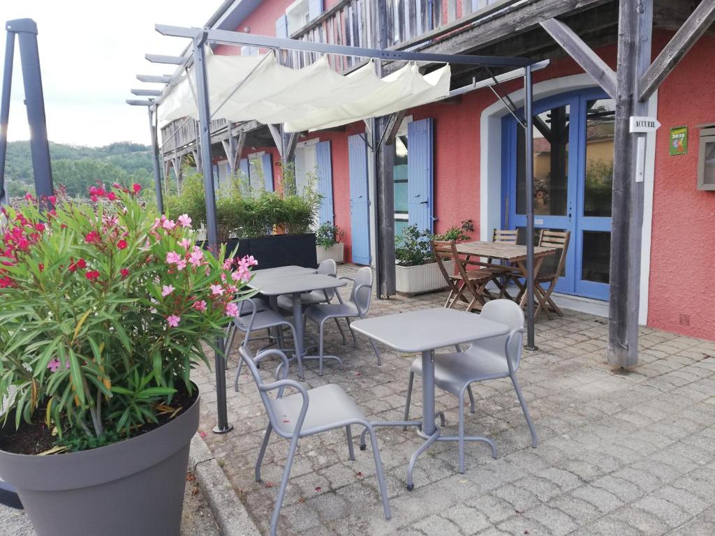 an outdoor patio with tables and chairs and flowers at Hôtel Rose des Vents in Baix
