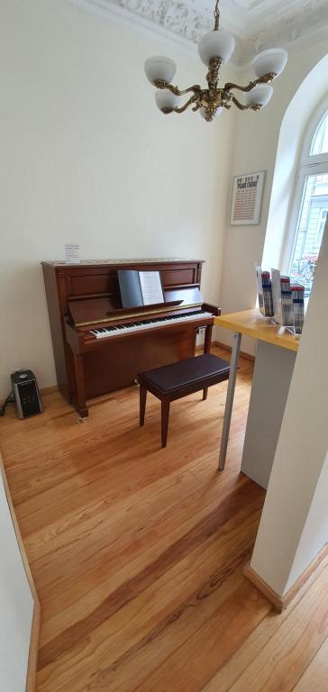 a piano in a living room with a wooden floor at Buch-Ein-Bett Hostel in Hamburg