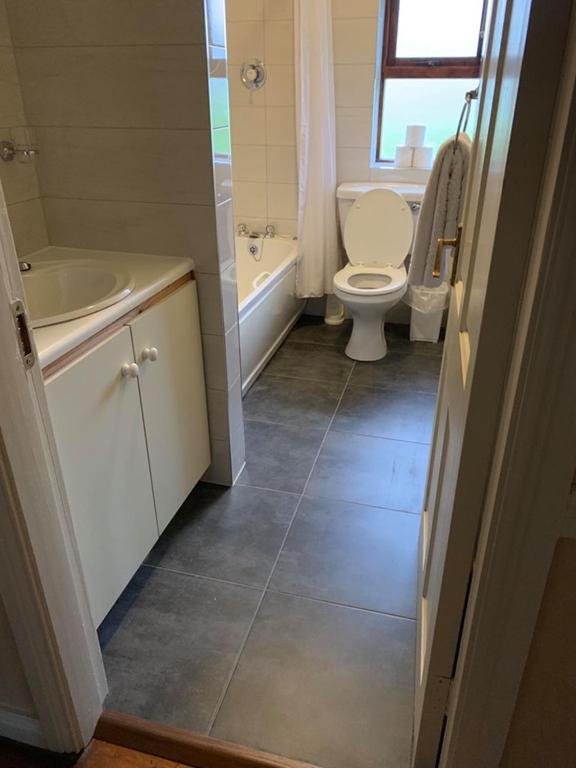 a bathroom with a toilet and a tub and a sink at Amber Cottage in Killarney
