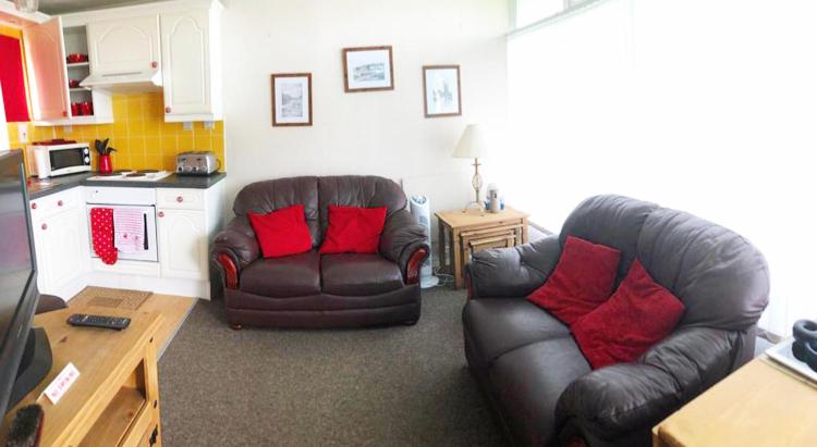 a living room with two leather chairs and a kitchen at Broadside Chalet Park No 90 in Norwich