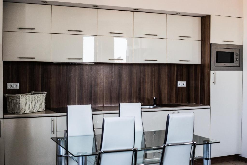 a kitchen with a glass table and white cabinets at Senator Warsaw Apartments in Warsaw