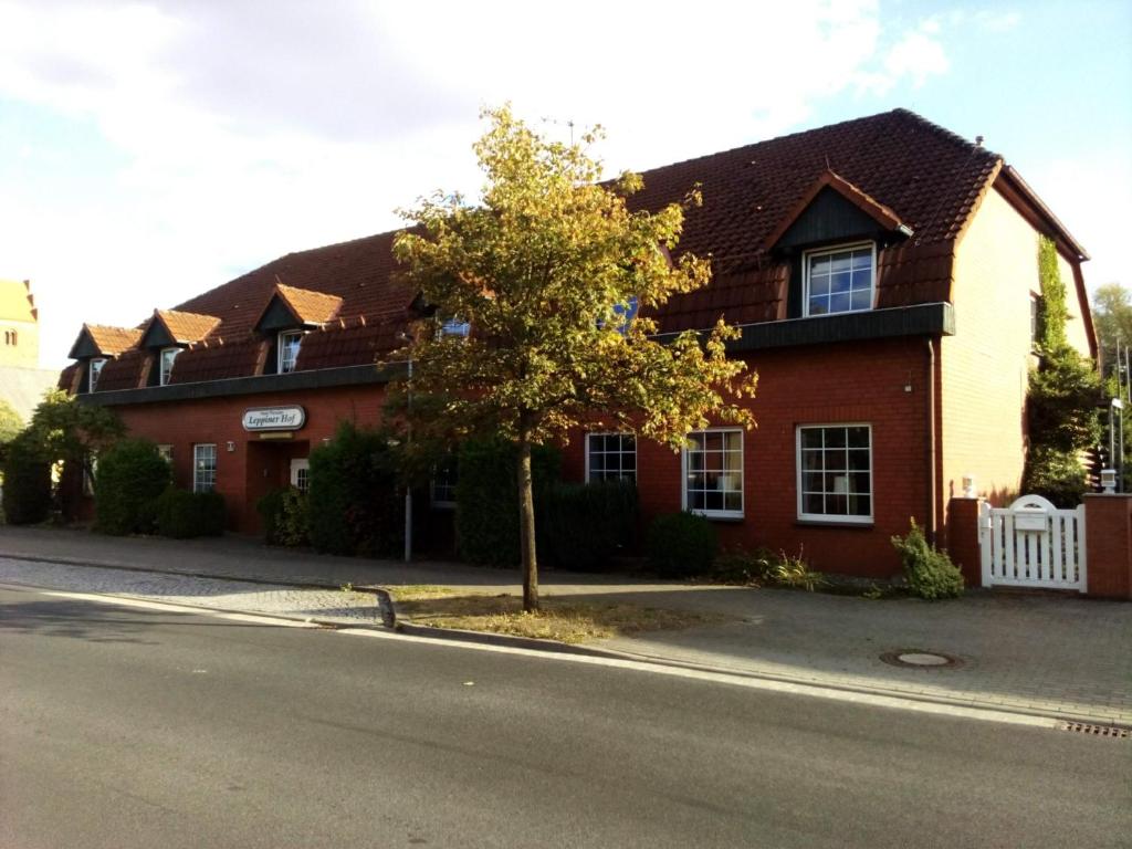 a house with a tree in front of a street at Hotel Leppiner Hof - B&B FRÜHSTÜCKSPENSION in Arendsee