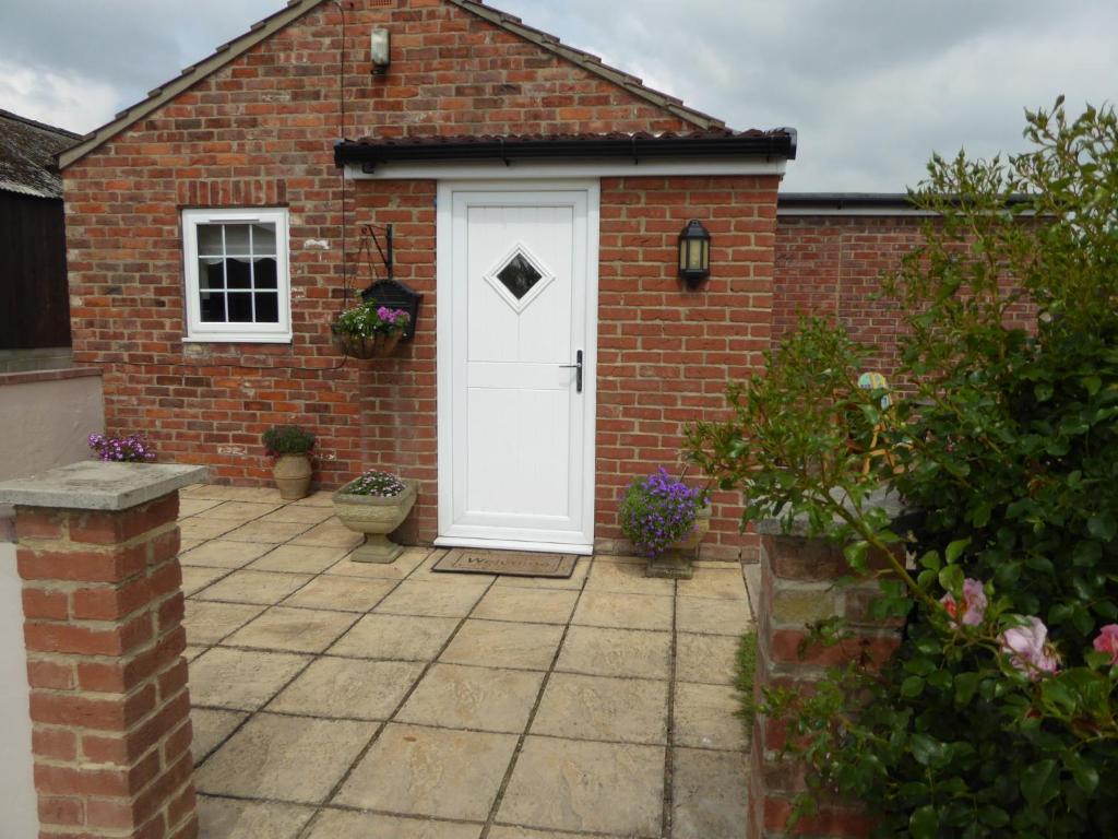 a brick house with a white door and a courtyard at High Oak Holiday Cottage in Thirsk