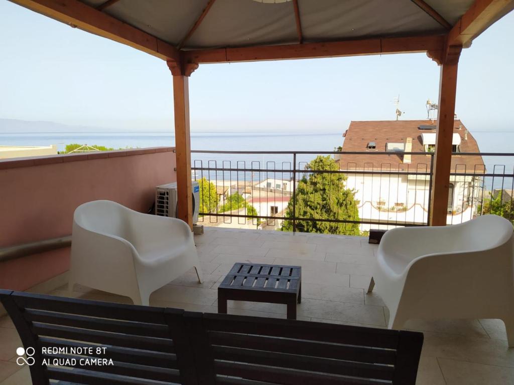 un patio con 2 sillas y una mesa en el balcón en Pozzo Lazzaro Apartments, en Santa Teresa di Riva