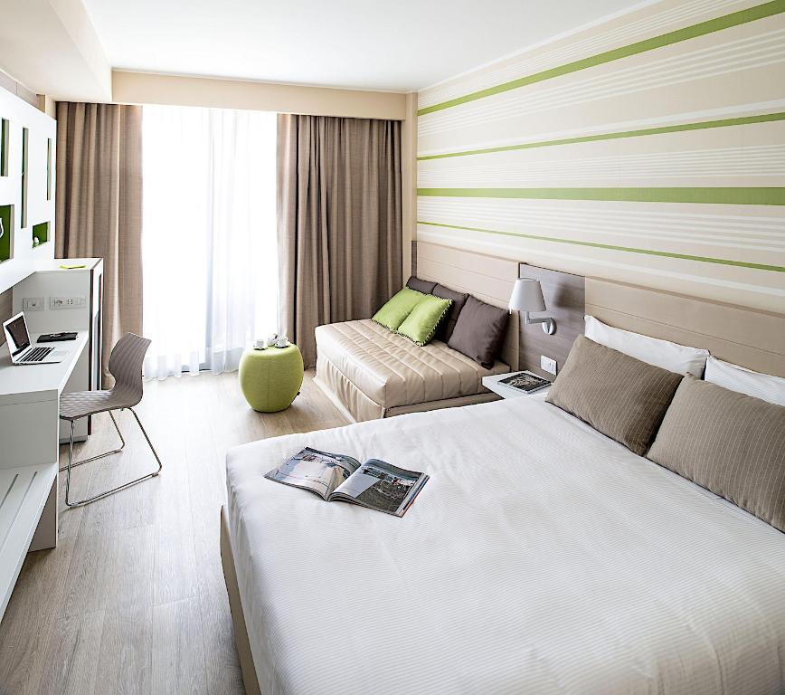 a hotel room with a bed and a couch at Enjoy Garda Hotel in Peschiera del Garda