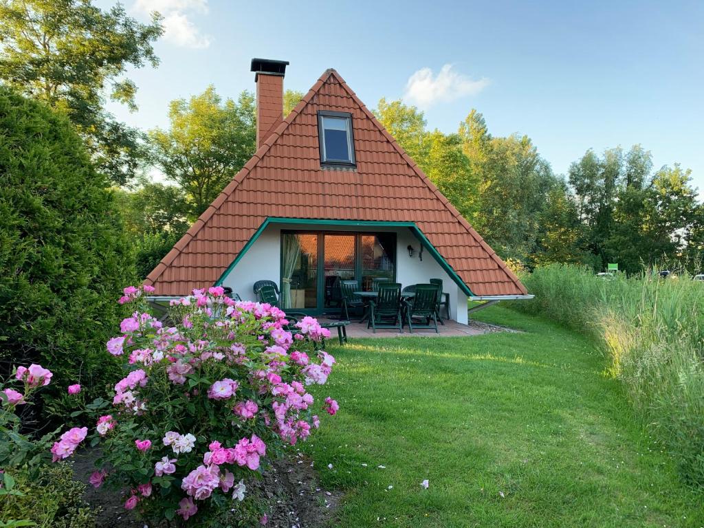 a small house with a pitched roof and some flowers at Ferienhaus Anna in Dorum Neufeld