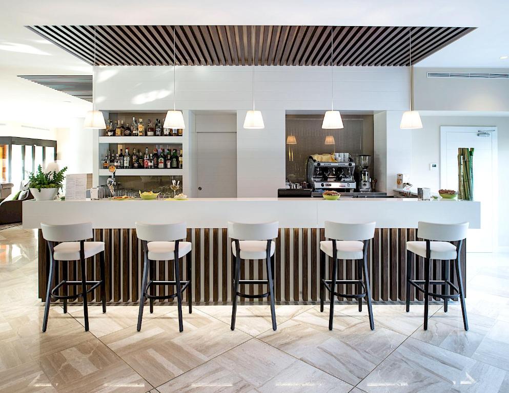 a kitchen with a large white counter with stools at Enjoy Garda Hotel in Peschiera del Garda