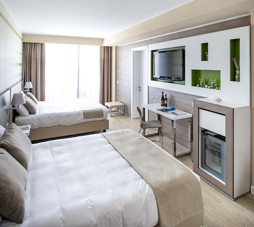 a hotel room with two beds and a television at Enjoy Garda Hotel in Peschiera del Garda
