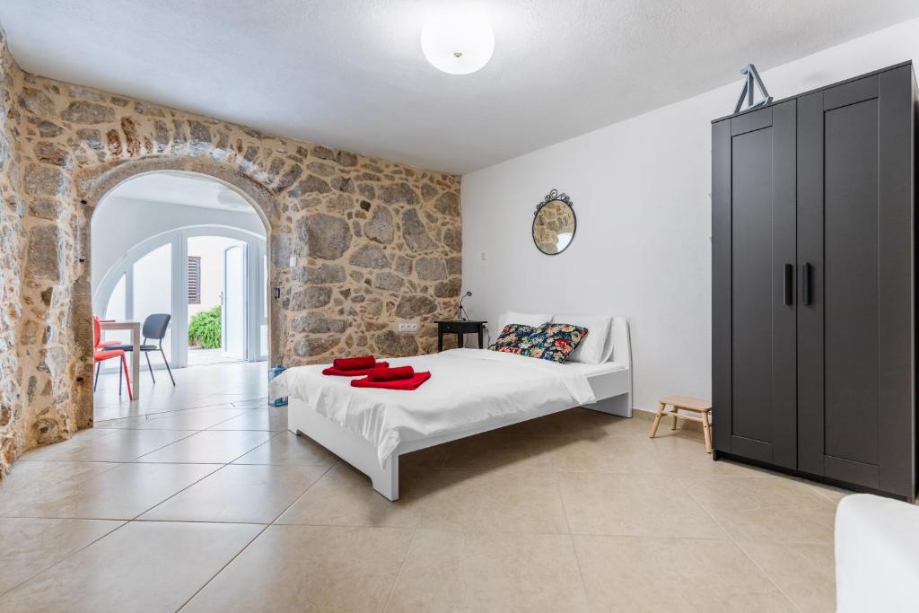 a bedroom with a bed and a stone wall at Apartman Otto in Punat