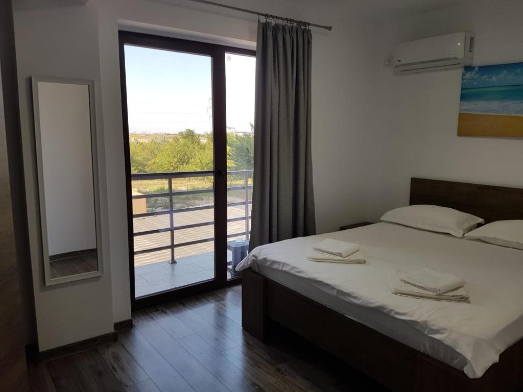 a bedroom with a bed and a view of a balcony at Vila La Matache in Eforie Nord