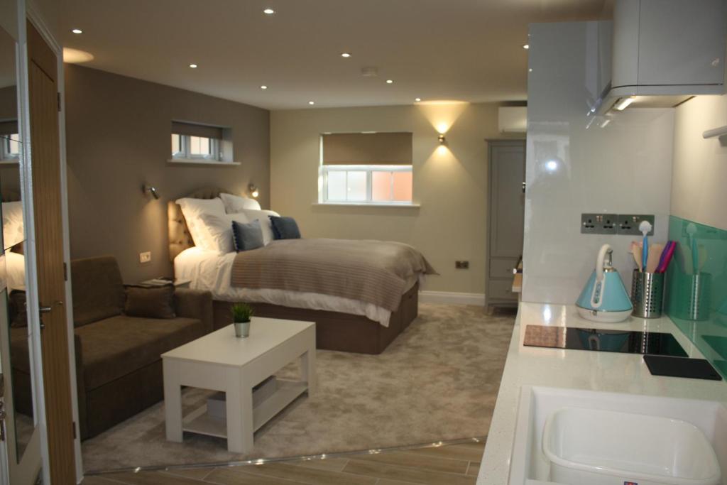 a bedroom with a bed and a couch and a sink at Frinton Escapes in Frinton-on-Sea