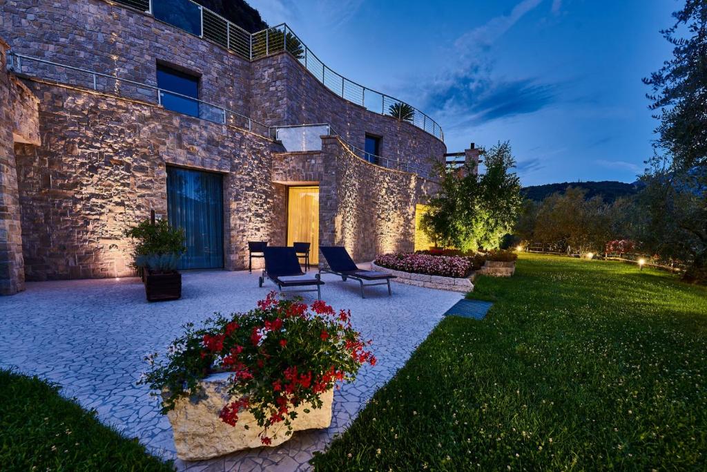 een stenen gebouw met een patio met stoelen en bloemen bij Agriturismo Maso Botes in Arco