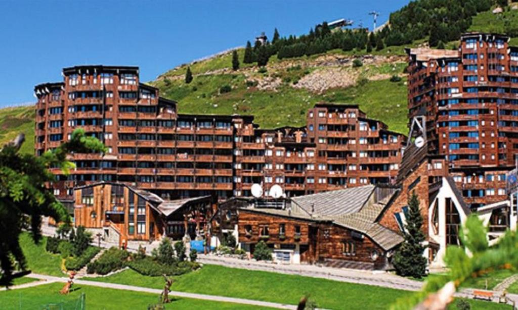 a large building with a green hill in the background at Residence Les Fontaines Blanches - maeva Home in Avoriaz