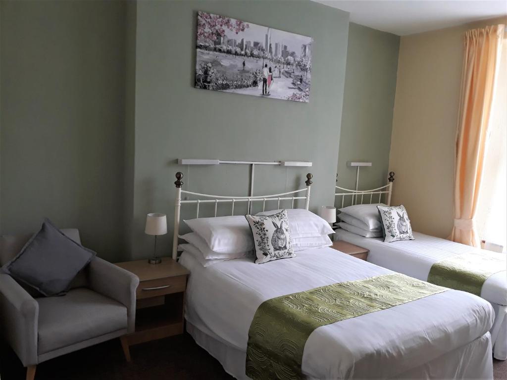 une chambre d'hôtel avec deux lits et une chaise dans l'établissement Ashfields, à Llandudno