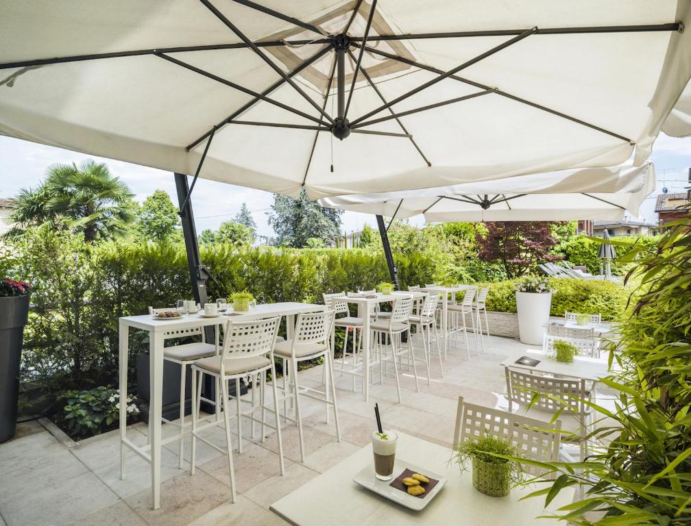 a patio with tables and chairs under umbrellas at Enjoy Garda Hotel in Peschiera del Garda