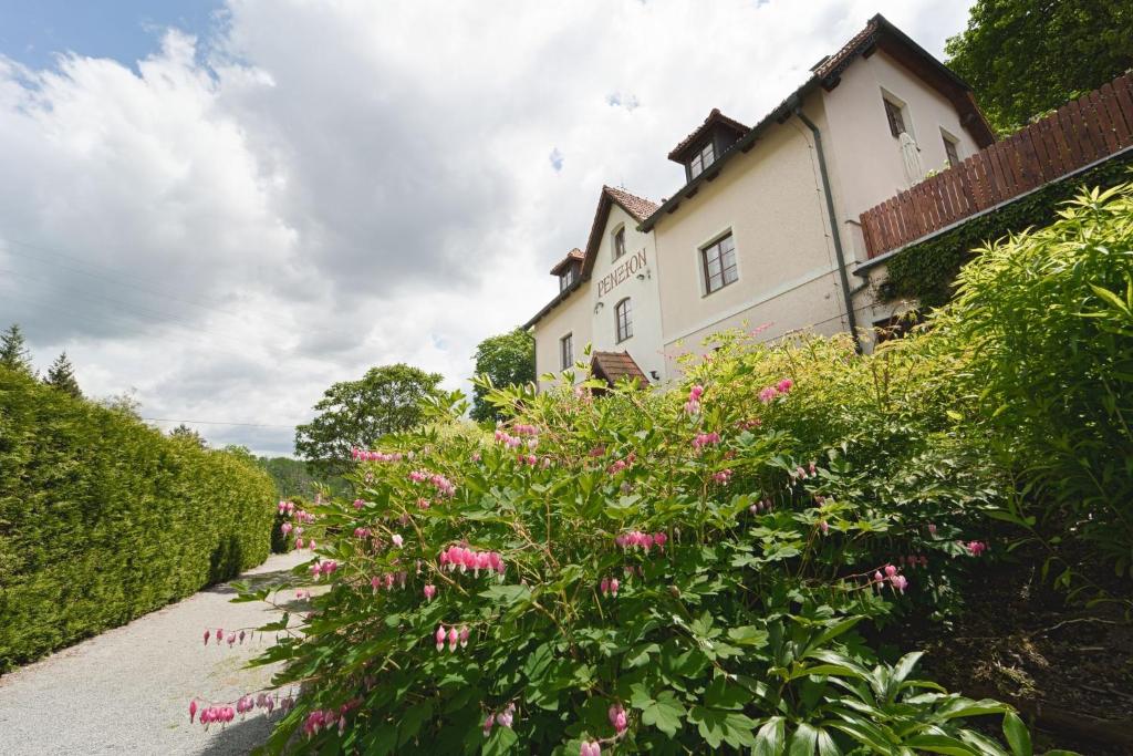 a house with pink flowers on the side of a sidewalk at Penzion Onyx in Český Krumlov