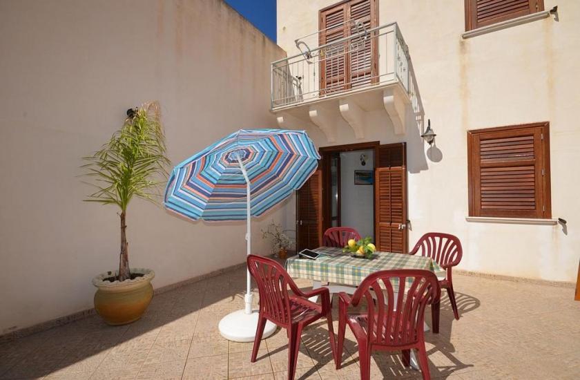 a table with chairs and an umbrella on a patio at Casa Sarina in San Vito lo Capo