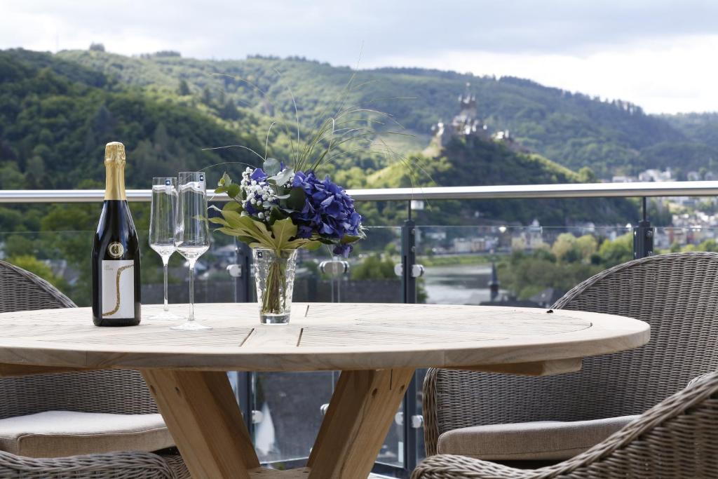 a table with a bottle of wine and flowers on it at Rooftop Moselsuite in Cochem