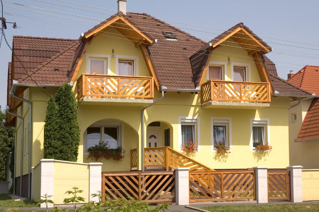 ein großes gelbes Haus mit Holzbalkonen in der Unterkunft Erika Appartementhaus in Keszthely