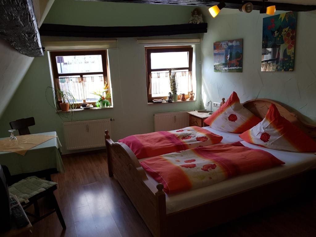 a bedroom with a bed with red sheets and two windows at Zum Burgtörle in Walldürn