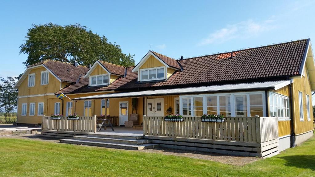 a yellow house with a porch and a fence at Björkängs Vandrarhem in Tvååker