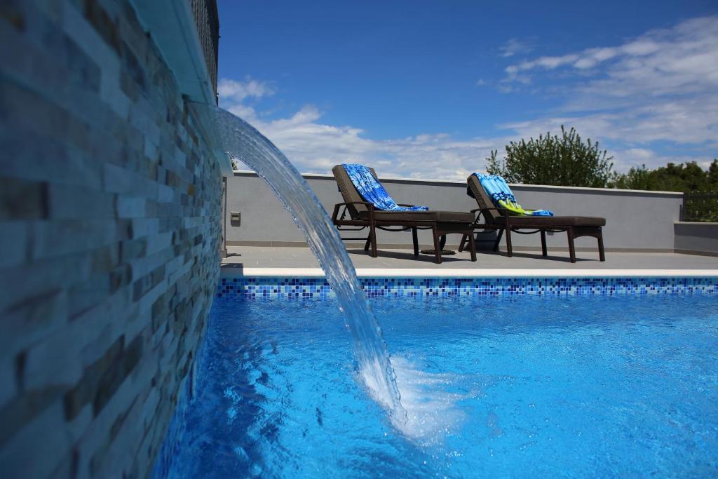 a pool with two chairs and a water fountain at Vacation home Meri in Mirce