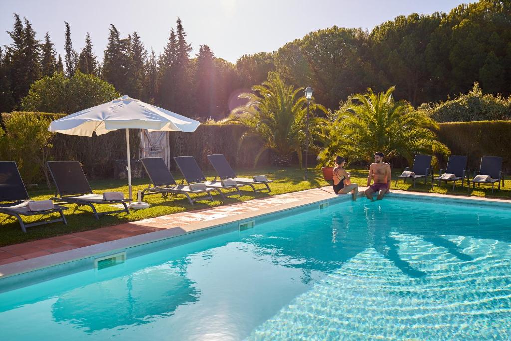 Deux personnes se tiennent à côté d'une piscine dans l'établissement Quinta dos Machados Countryside Hotel & Spa, à Mafra