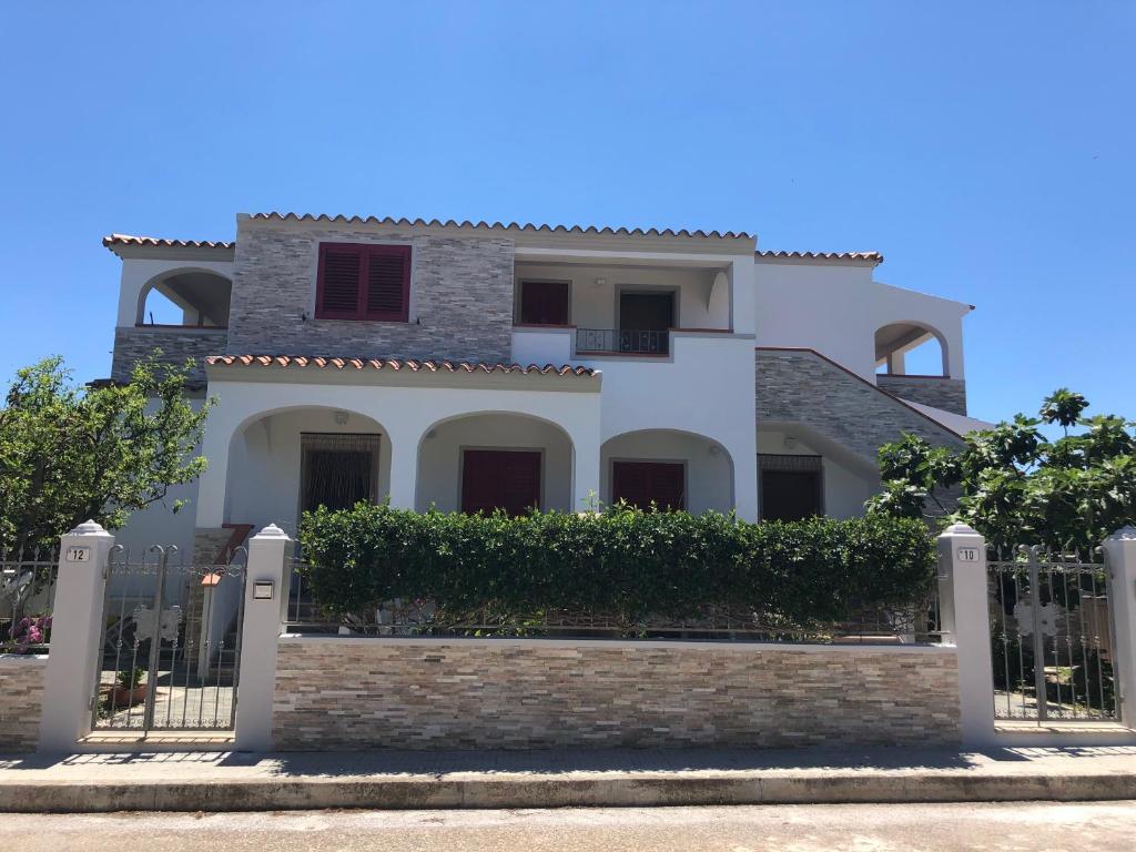 een groot wit huis met een hek bij Appartamento in Villa Andreina in Orosei