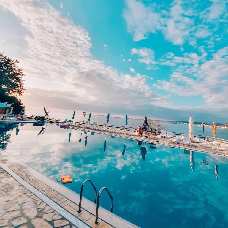 a swimming pool with chairs and the water at Renissa's Beach Suite in Vlorë
