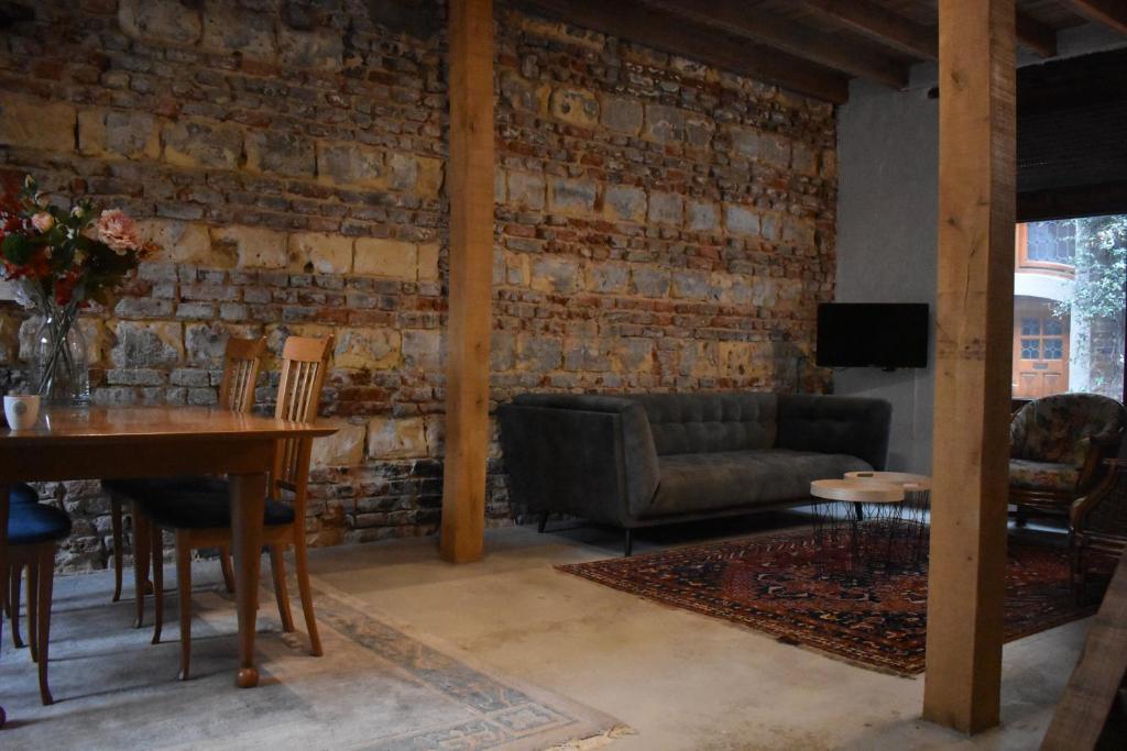 a living room with a table and a brick wall at Roermond Uniek Stadspand, compleet woonhuis in Roermond
