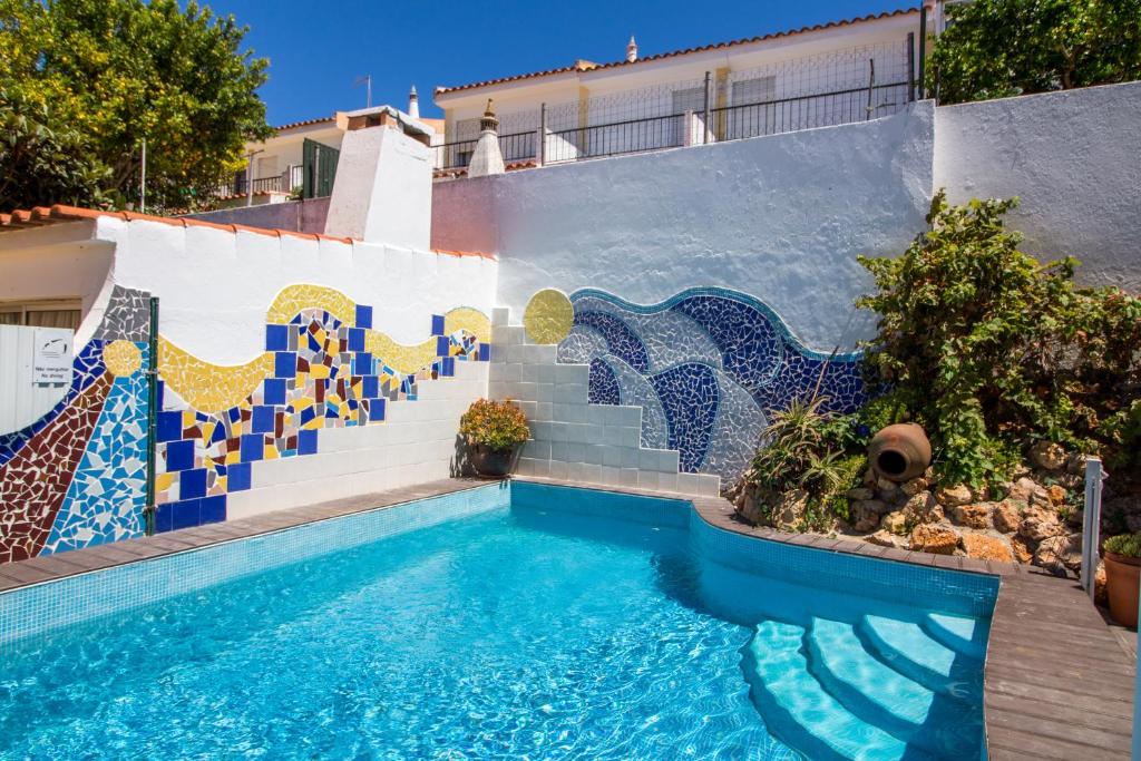 una piscina con un mural de mosaico en el lateral de un edificio en Albuera Villa en Albufeira