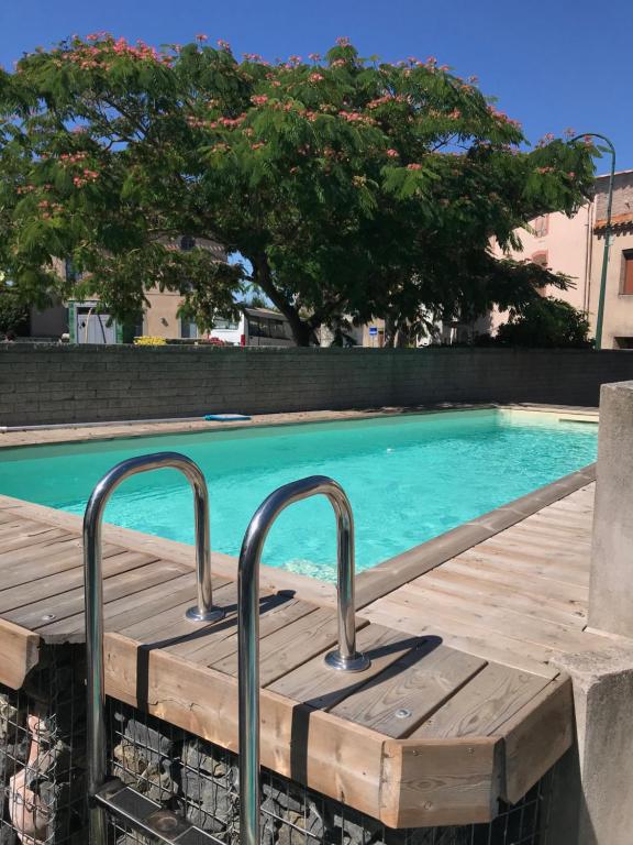a pool with a wooden boardwalk next to a swimming pool at l'Ecrit Vin in Rustiques