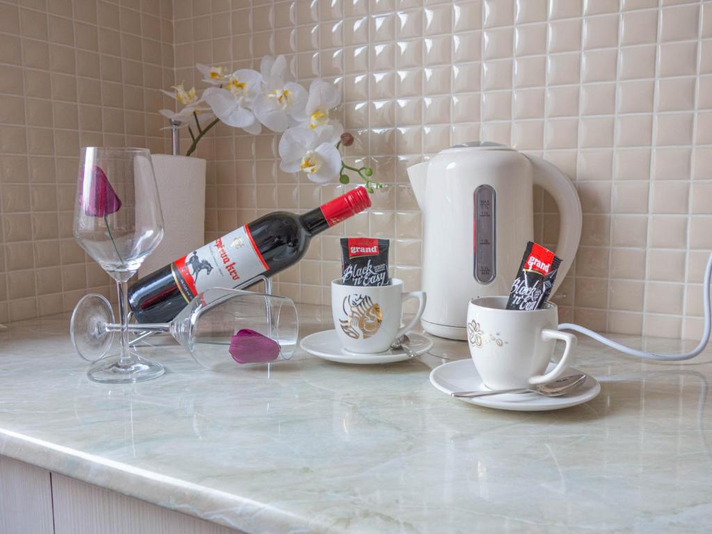 a bottle of wine and two cups on a counter at Angellina Apartmani in Sremska Mitrovica