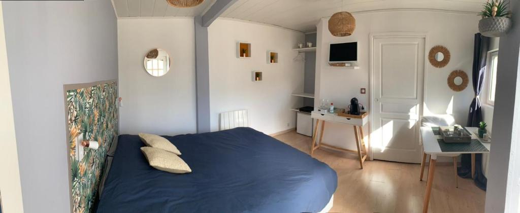 a bedroom with a blue bed and a desk at Les chambres du Bonheur in Fontaine-sous-Jouy