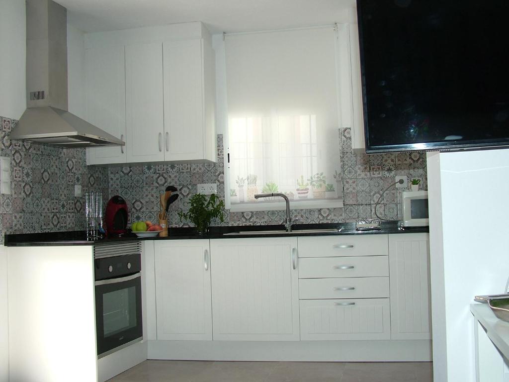 eine weiße Küche mit weißen Schränken und einem Fenster in der Unterkunft Casa Fuente Alta in Otívar