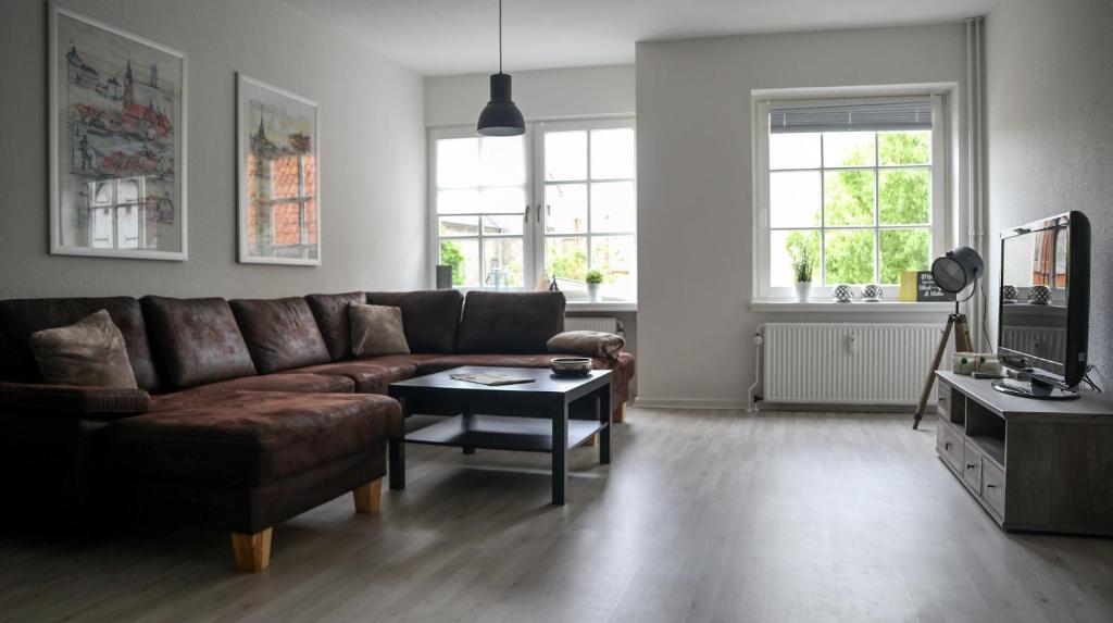 a living room with a brown couch and a table at Kapitainskoje direkt am Hafen Flensburgs in Flensburg