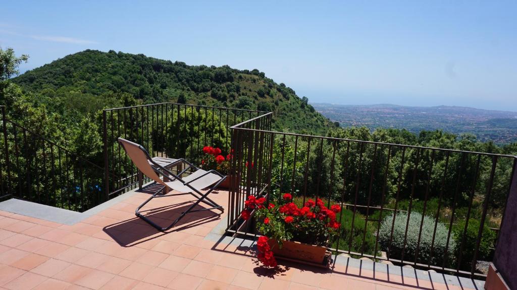 einen Balkon mit einem Stuhl und Blumen auf einem Berg in der Unterkunft Casa Etnea in Trecastagni