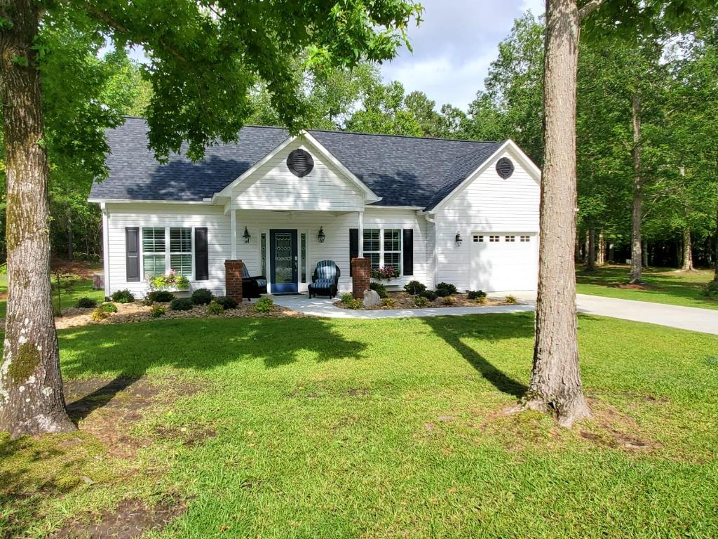 a white house with trees in the yard at Virginia's Country Cottage in Jacksonville