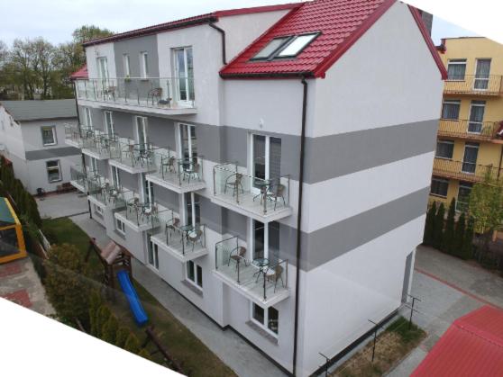 een groot wit gebouw met balkons en een rood dak bij Hotelik Neptun in Ustronie Morskie