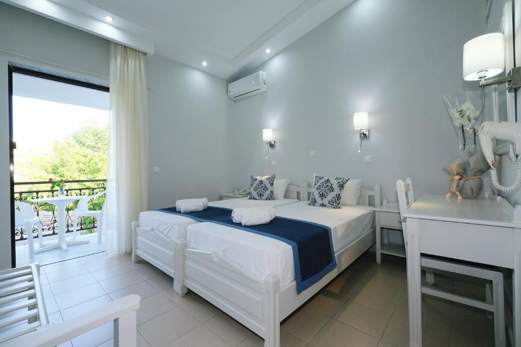 Habitación blanca con cama y balcón. en Ifestos Hotel, en Mirina