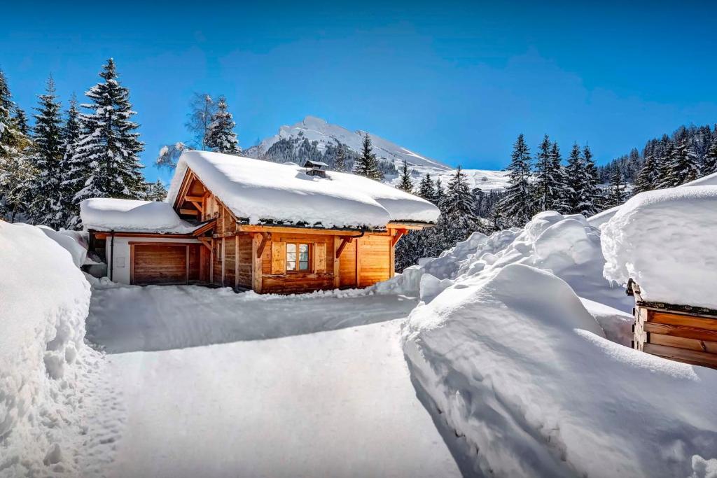 a log cabin covered in snow in the mountains at Chalet Hollygotty - OVO Network in La Clusaz