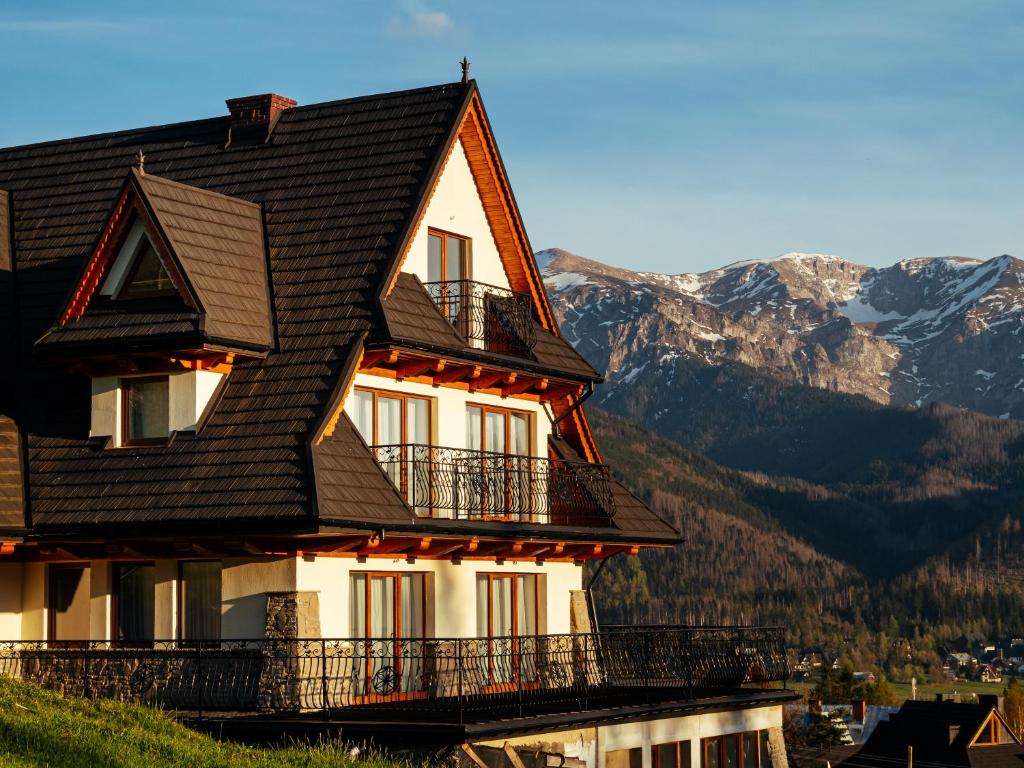 una casa en una colina con montañas en el fondo en Strama Kościelisko, en Kościelisko