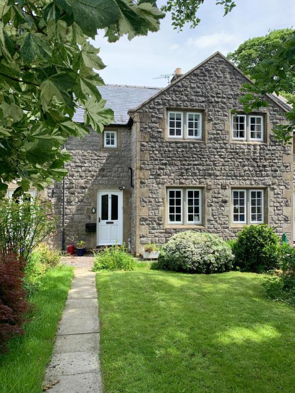 a stone house with a white door and a yard at Cathedral View in Tideswell