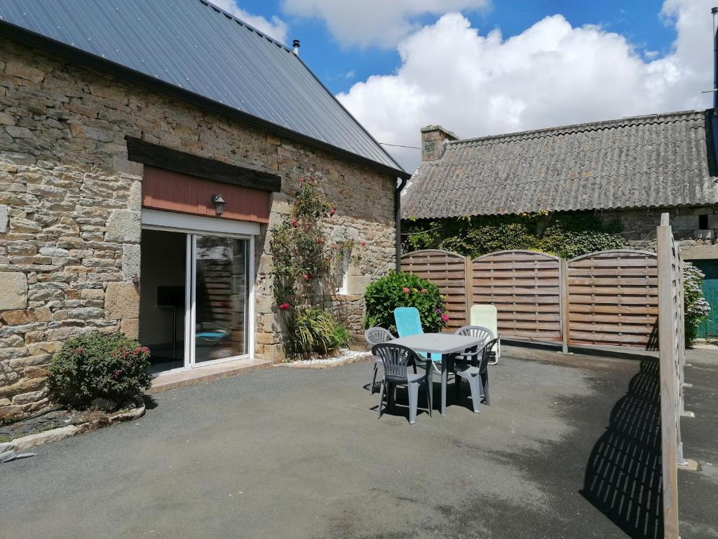 een terras met een tafel en stoelen naast een gebouw bij Ar baradoz in Guiler-sur-Goyen