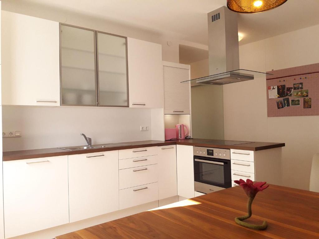 a kitchen with white cabinets and a wooden table at Traumapartment Pöstlingberg, reservierter Parkplatz, 4 Schlafzimmer in Linz