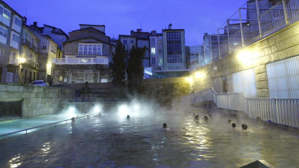 un grupo de personas nadando en una fuente por la noche en Polvorín en Ourense