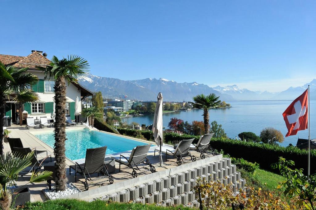 a swimming pool with chairs and a view of the water at B&B Corseaux Beach & Riviera Beach in Vevey