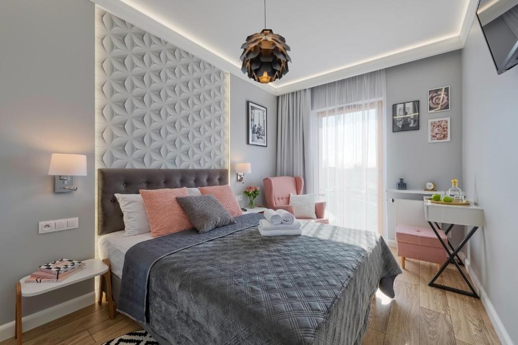 a bedroom with a bed and a desk and a window at atHome Suites in Kraków